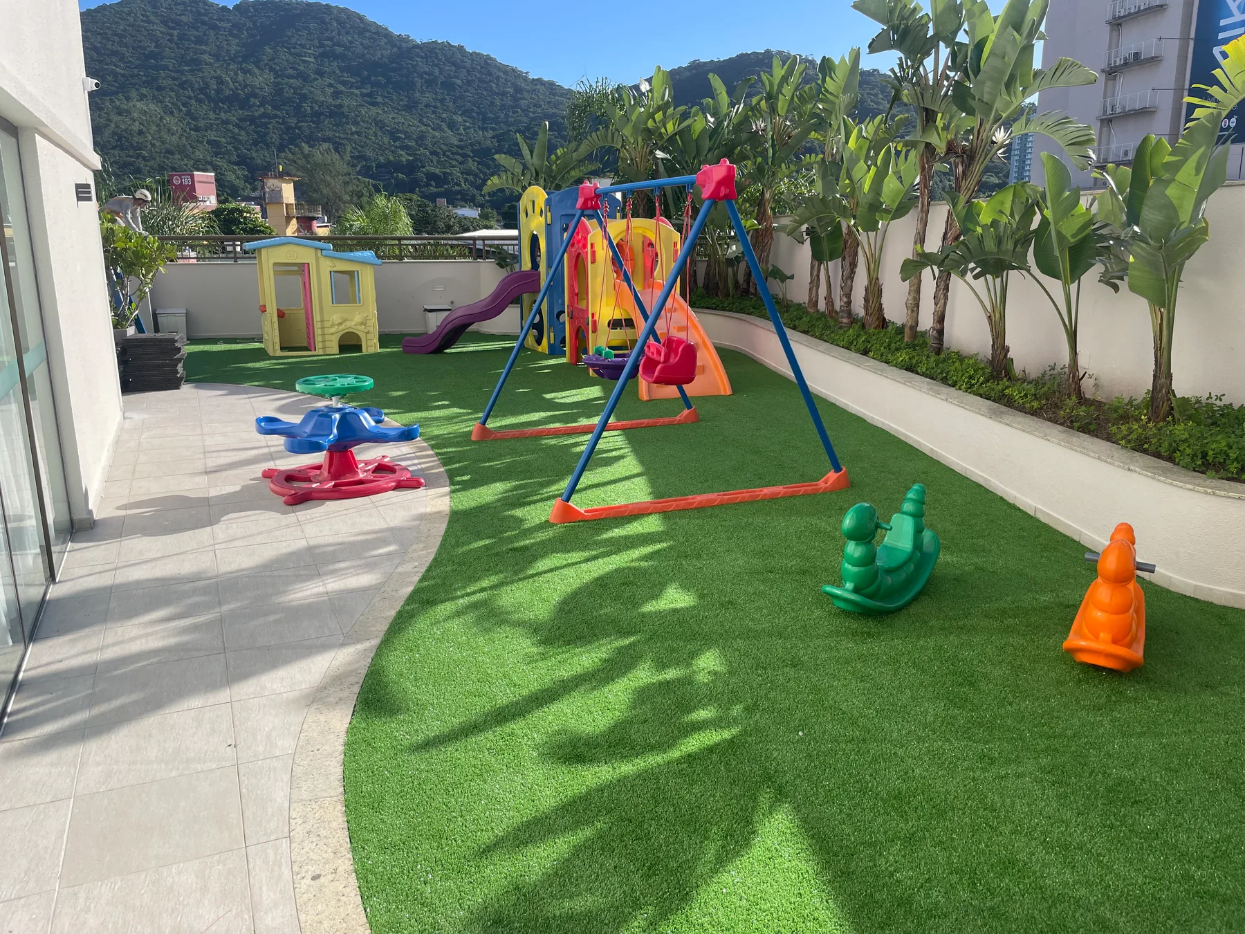 Área de lazer de condomínio residencial com grama sintética instalada pela Decor Gramas em Itajaí, SC